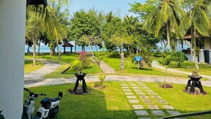 A tropical resort with a paved pathway, palm trees, and a view of the sea. - Grand Elty Krakatoa (Kalianda)