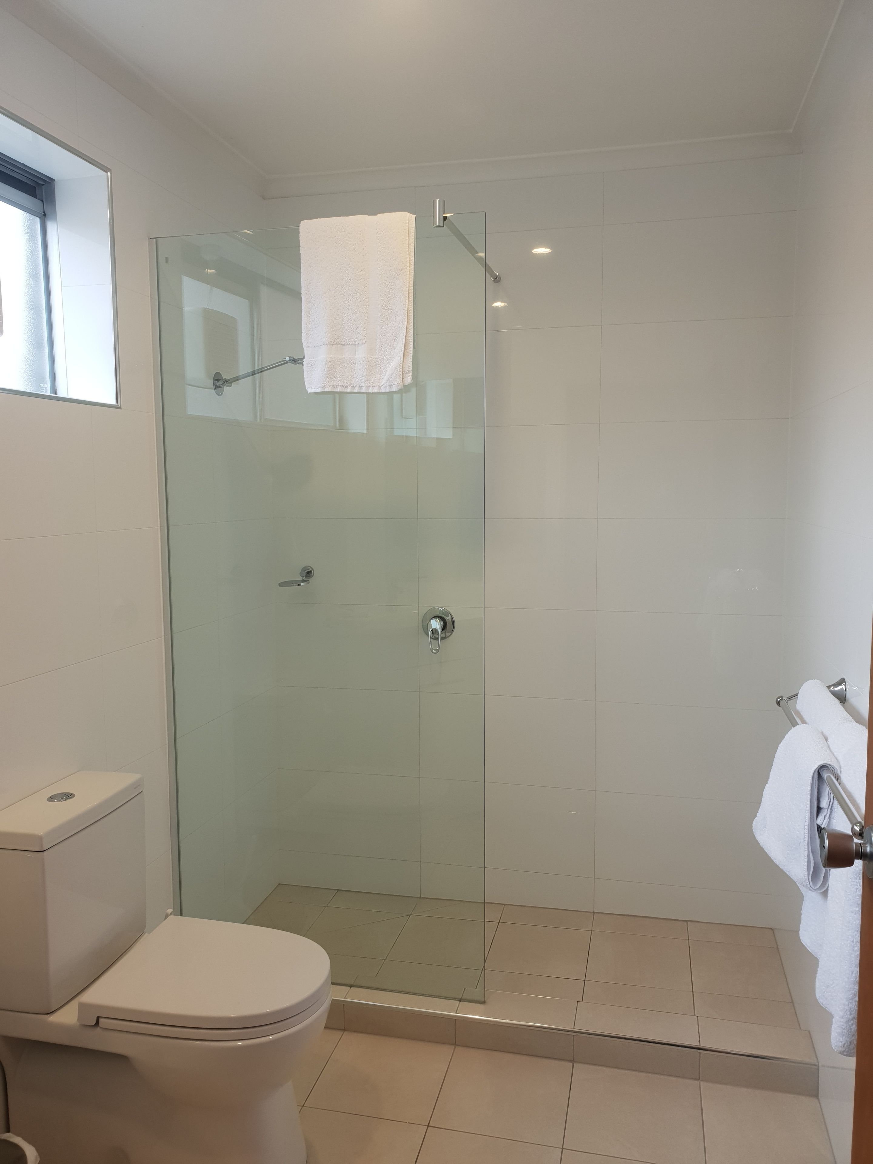 A bathroom with a glass shower enclosure, a toilet, and a sink.