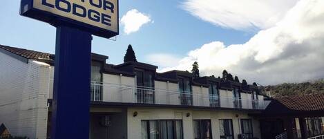 A sign for Argyle Motor Lodge with a white building and a blue sign post.