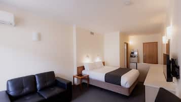 A hotel room with a bed, a sofa, a small table, a TV, and a microwave.