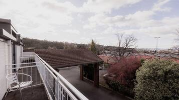 Enjoy a peaceful view of the surrounding neighborhood from this balcony with a seating area and metal railing.