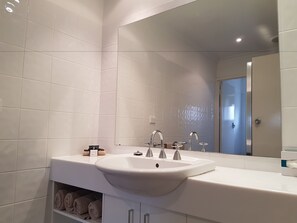A modern bathroom with white tiles, a large mirror, a white sink, and a towel rack. - Centralpoint Motel (Wagga Wagga)