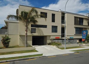 A modern hotel with a flat facade, multiple windows, and a parking lot.