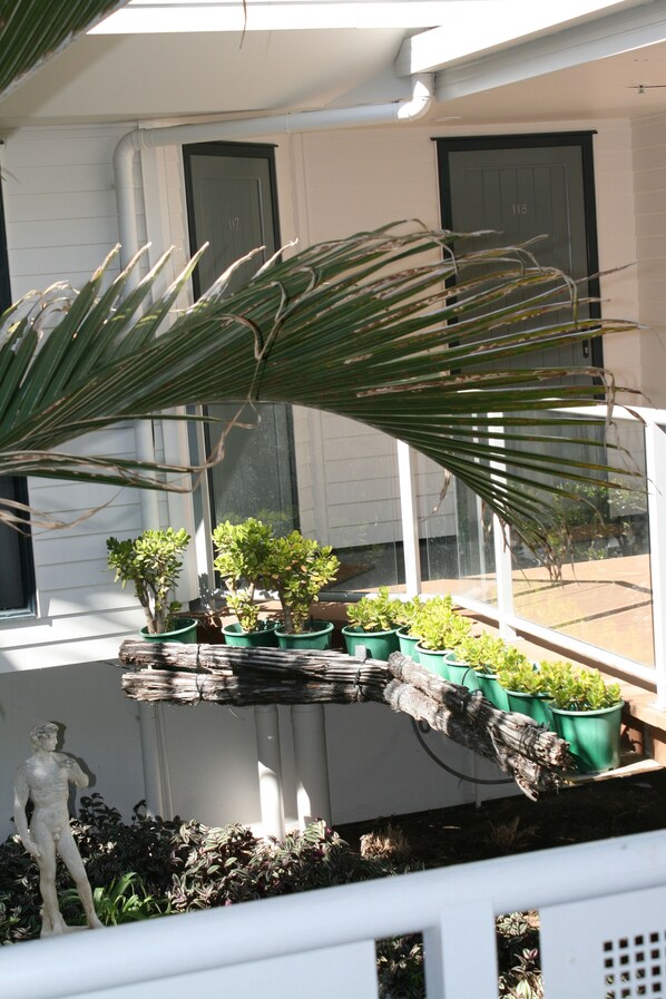 A balcony with potted plants and a statue.