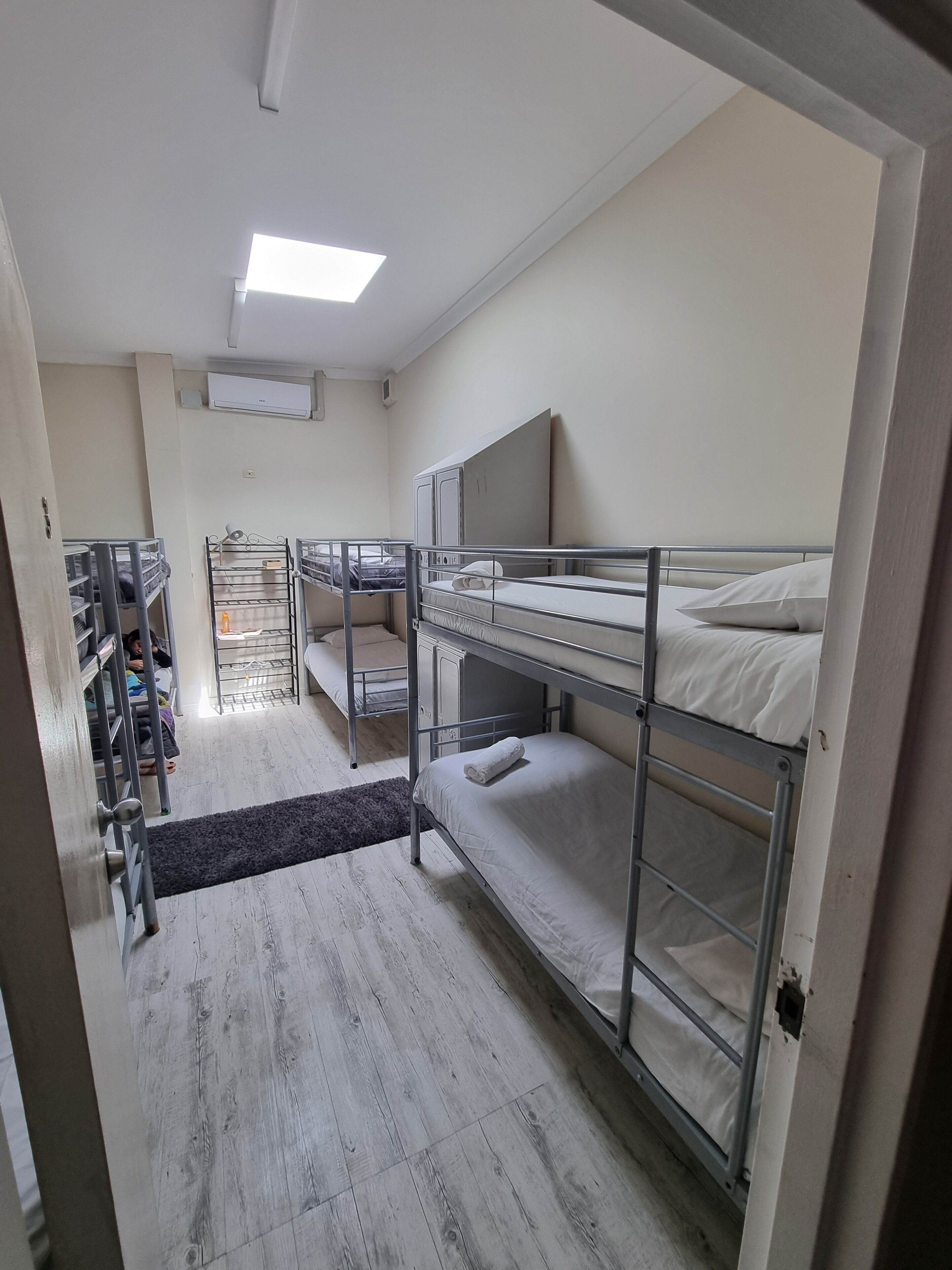Um quarto de estudante com beliches, uma escrivaninha e uma cadeira.