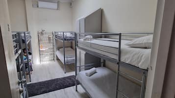 Um quarto de estudante com beliches, uma escrivaninha e uma cadeira.