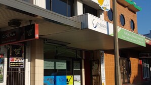 A building with a sign for 'The Entrance Backpackers' and a cinema. - The Entrance Backpackers - Hostel (The Entrance)