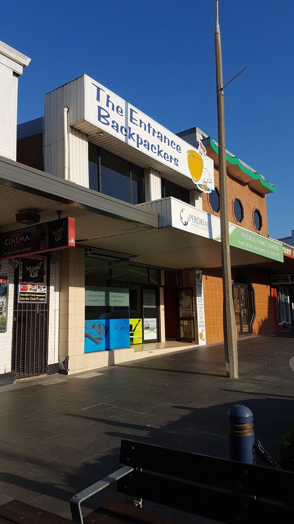 Un edificio con un letrero que dice 'The Entrance Backpackers' y un cine.