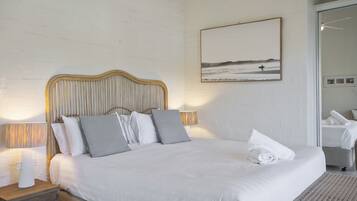 A neatly made bed with a wooden headboard, a bedside lamp, and a framed picture on the wall.