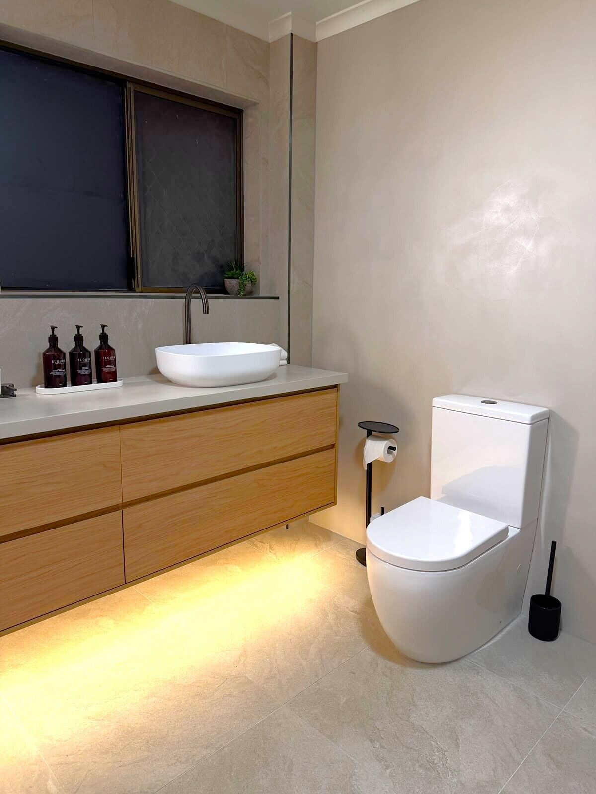 Une salle de bain moderne avec un lavabo blanc, un meuble-lavabo en bois et des toilettes.