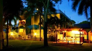 A building with a covered outdoor seating area and a well-lit entrance. - Sky View Units (Bowen)