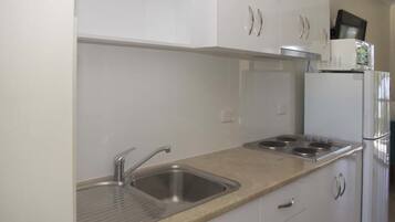 A modern kitchen with a stainless steel sink, a stove, and white cabinets.