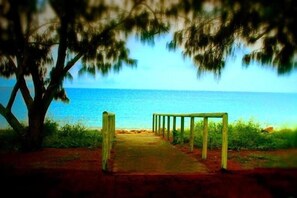 A pathway leading to a beach with a wooden structure in the middle. - Sky View Units (Bowen)