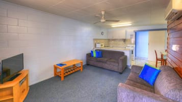 A compact living space with a kitchenette, a television, a sofa, and a small table.
