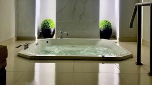 A modern bathroom with a large rectangular bathtub, two potted plants, and a minimalist design. - Hotel Velario (Tijuana)