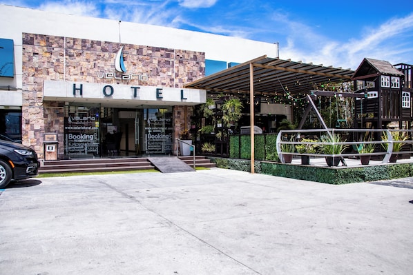 A hotel with a stone facade, a covered entrance, and a play area.