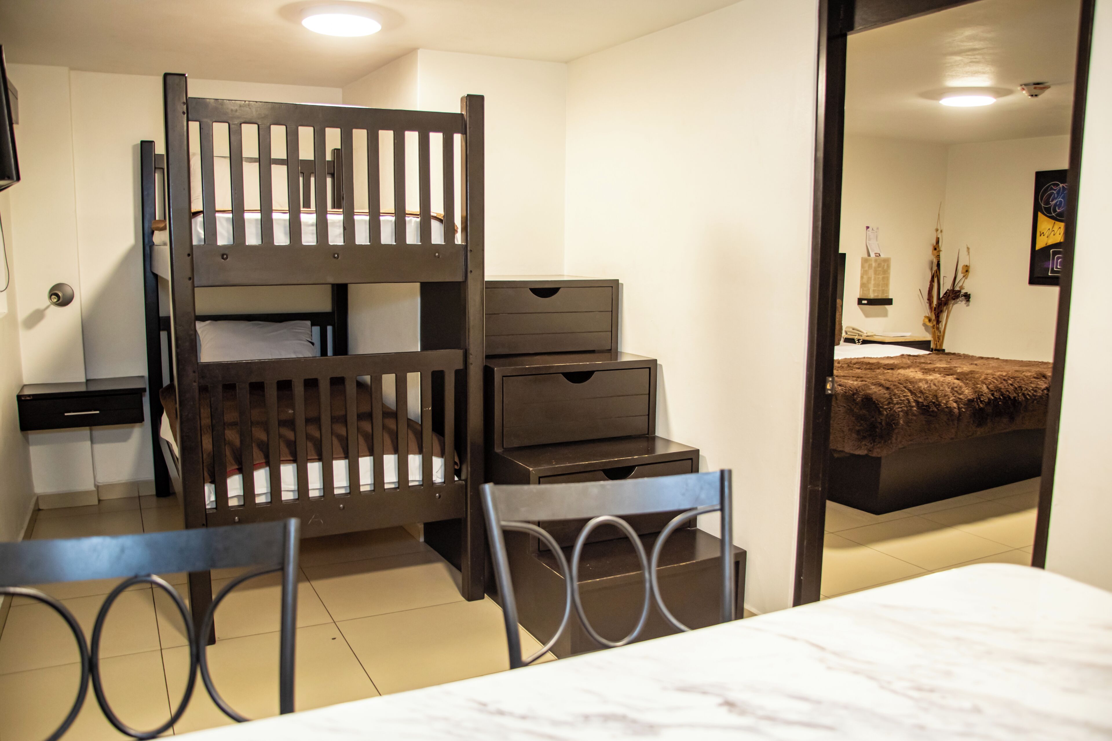 A bunk bed with a desk and chair, a small dresser, and a bathroom visible through an open door.
