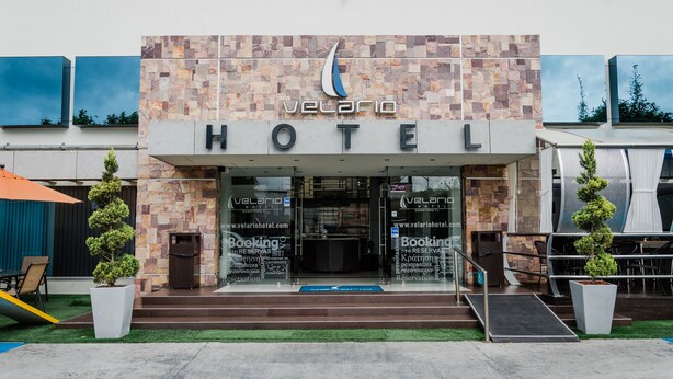 A hotel entrance with a stone facade, a logo above the name, and a sign for 'Velario Hotel'. - Hotel Velario (Tijuana)