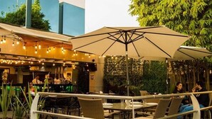An outdoor patio with tables and chairs, umbrellas, and string lights. - Hotel Velario (Tijuana)