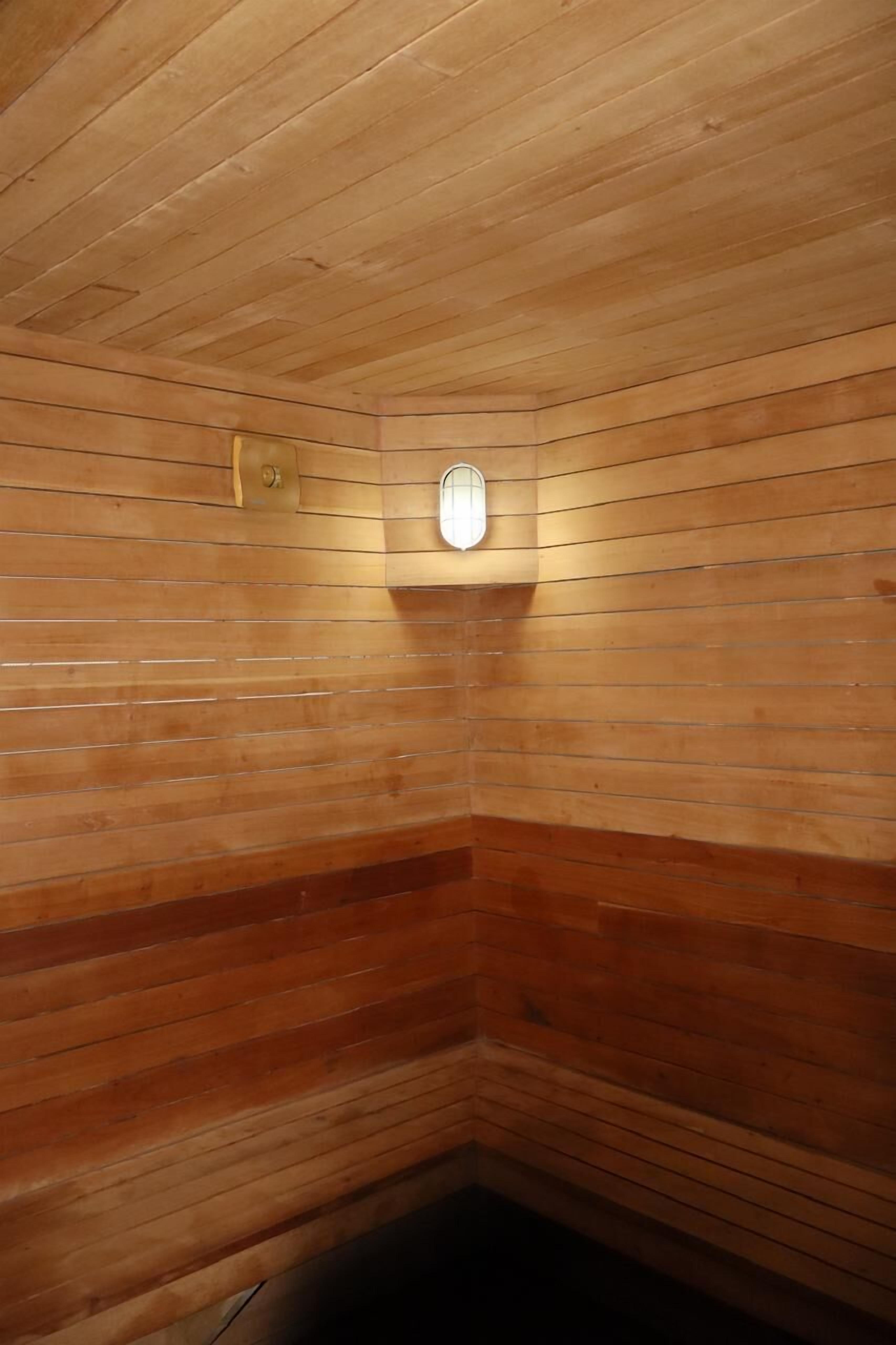 Una sauna de madera con paredes de listones y una ventana pequeña.