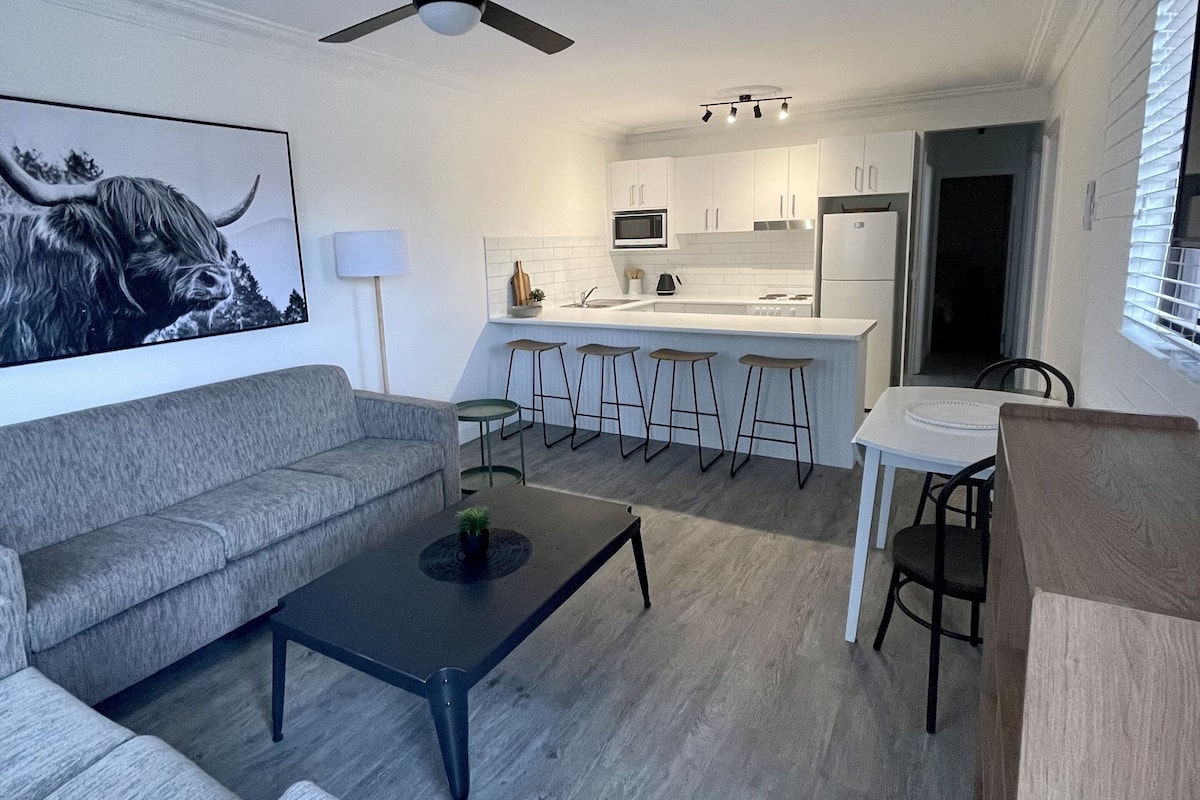 A modern living room with a grey sofa, a coffee table, and a ceiling fan.