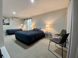 Un dormitorio moderno con dos camas, un escritorio, una silla y una lámpara.
