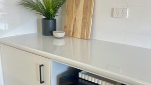 A kitchen with a microwave, a potted plant, and a wooden cutting board on the countertop.
