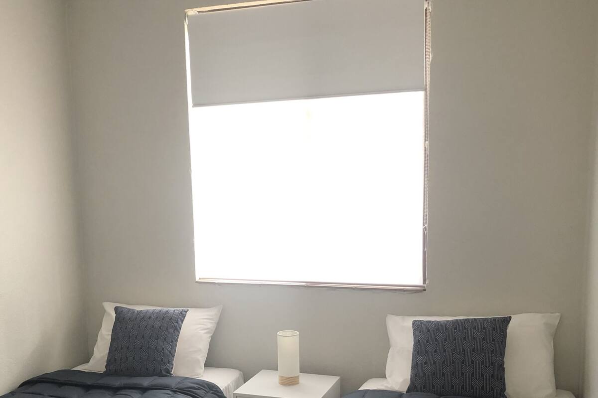A bedroom with two beds, a nightstand, and a window.