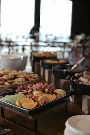 A buffet with various food items including fruits, pastries, and meats.