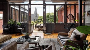 A spacious patio with a glass wall, wicker furniture, and a hanging chair. - Cleveland Estate (Lancefield)