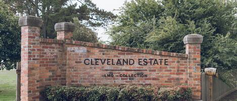 A brick wall with the text "CLEVELAND ESTATE" and "LMG - COLLECTION" indicating a real estate property.