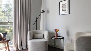 A modern living room with a grey armchair, a small round table with a vase, and a floor lamp.