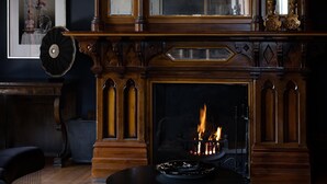 A room with a wooden fireplace, a framed picture on the wall, and a table with a decorative bowl. - Cleveland Estate (Lancefield)