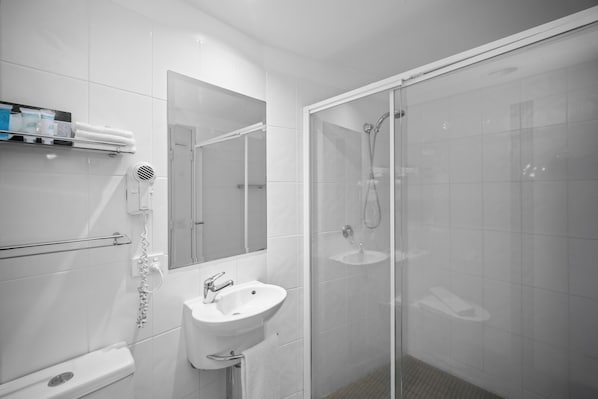 Un baño moderno con cabina de ducha de vidrio, un lavabo blanco y un espejo sobre el lavabo.