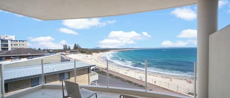 A balcony with a view of a beach and ocean.