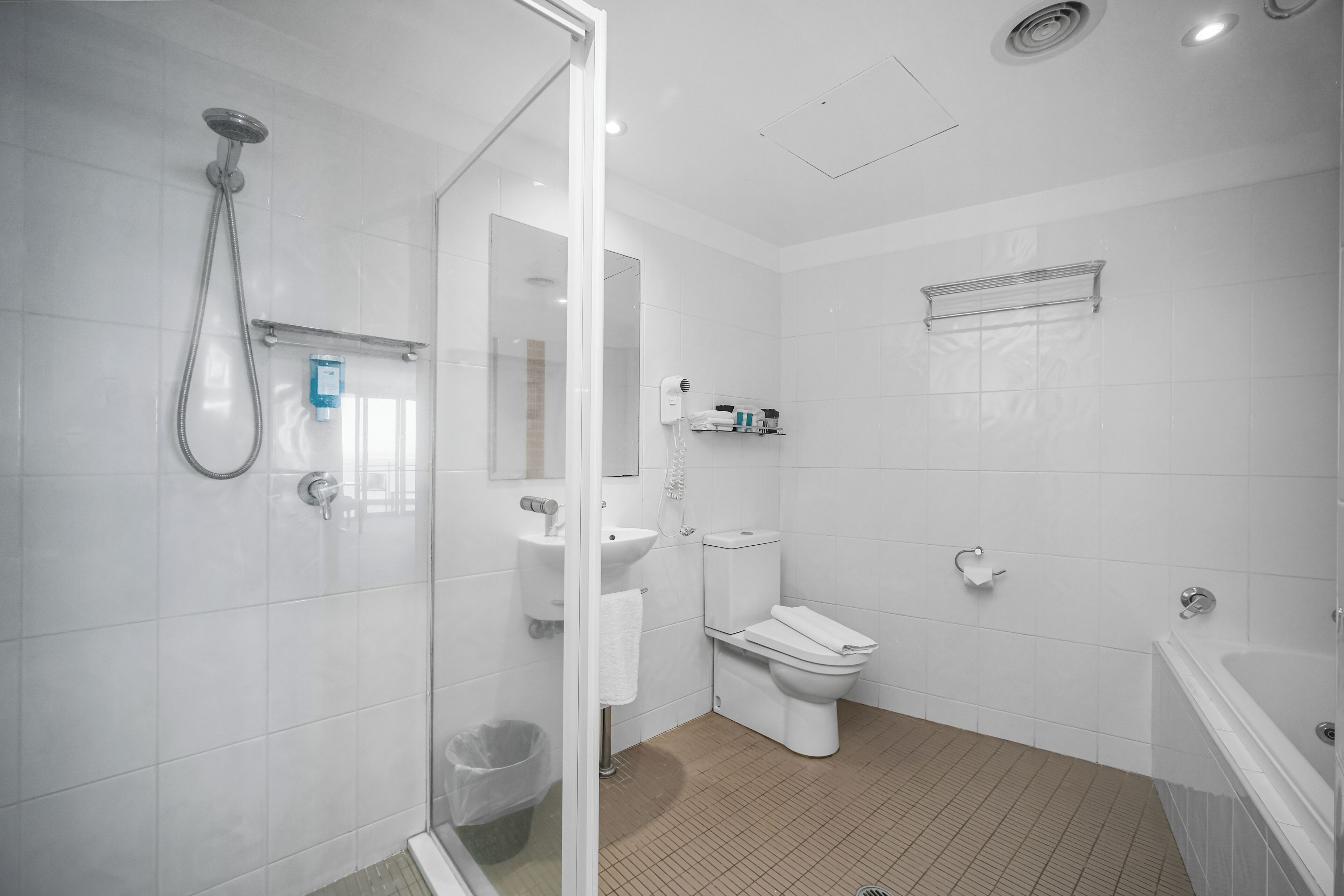 Un baño moderno con cabina de ducha de vidrio, inodoro, lavamanos y bañera.