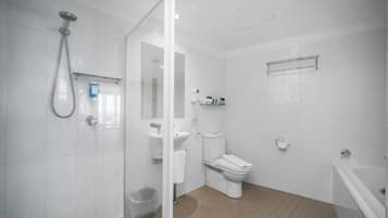 Un baño moderno con cabina de ducha de vidrio, inodoro, lavamanos y bañera.