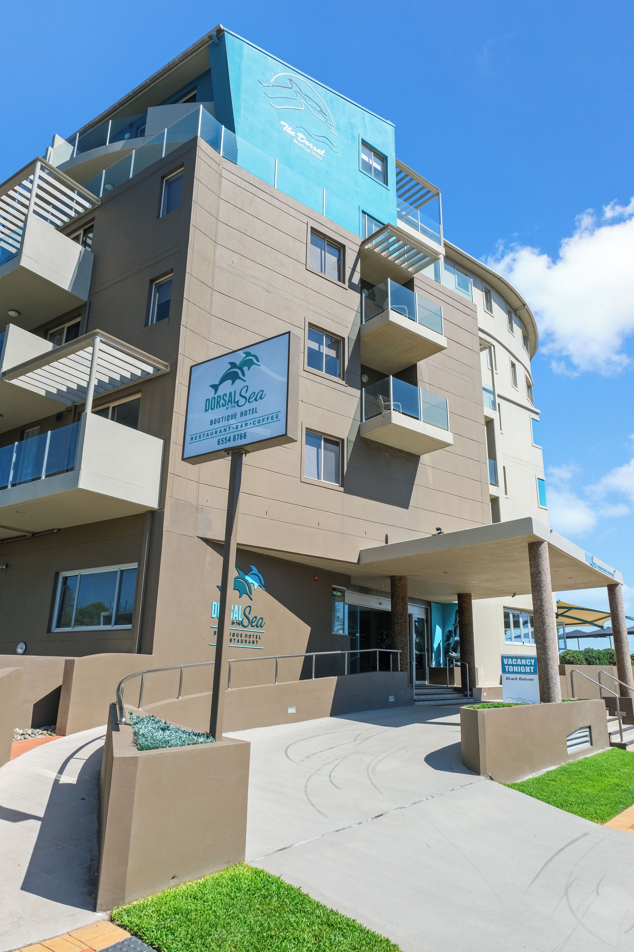 A multi-story building with a sign for DorsalSea Boutique Hotel and restaurant-bar-coffee.