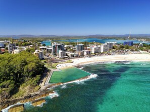 Un paisaje urbano costero con rascacielos, una playa y aguas azules cristalinas.