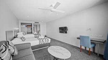 Een moderne hotelkamer met een bed, een bank, een bureau en een plafondventilator.
