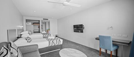 Una habitación de hotel moderna con cama, sofá, escritorio y ventilador de techo.
