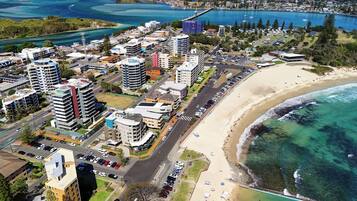 Un paisaje urbano costero con edificios altos, una playa y un puerto deportivo.