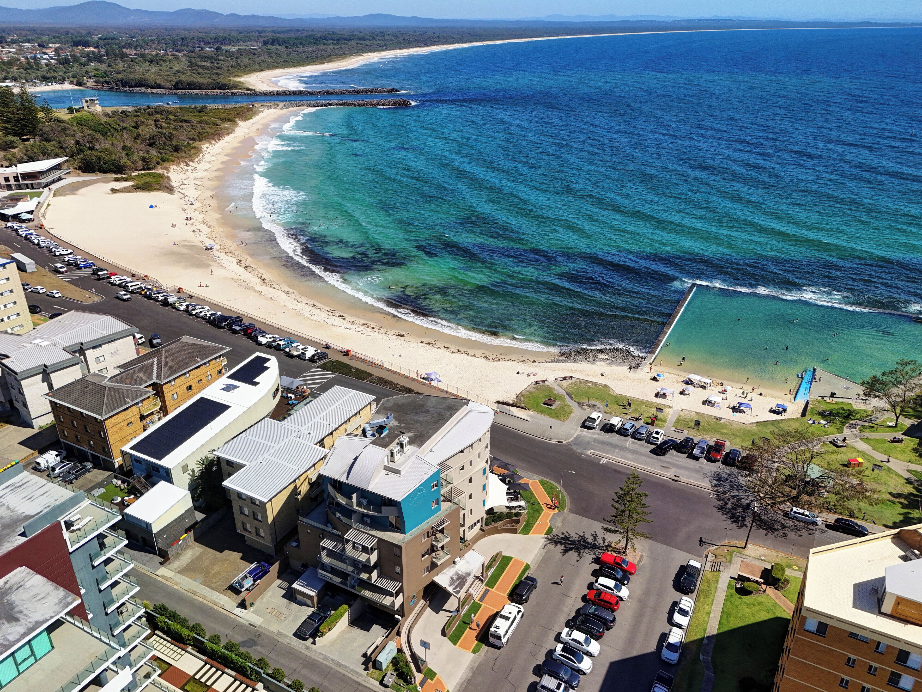 A coastal area with a beach, parking lots, and buildings.