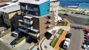 Un immeuble à plusieurs étages doté de balcons, d’un espace de stationnement et offrant une vue sur l’océan.
