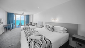 Une chambre d’hôtel avec deux lits, un bureau et une vue sur la mer.