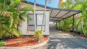A modern building with a covered patio area, surrounded by lush tropical vegetation. - Emerald Motel Apartments (Emerald)