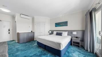 A hotel room with a large bed, a desk, a chair, and a painting on the wall.