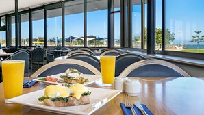Zona pranzo con tavoli, sedie e vista sul mare.