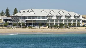 Un hotel sulla spiaggia con un design architettonico moderno, caratterizzato da numerosi balconi e un'imponente facciata in vetro.