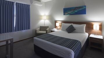 Une chambre d’hôtel avec un grand lit, un bureau, une chaise, deux tables de chevet avec des lampes et un tableau au mur.